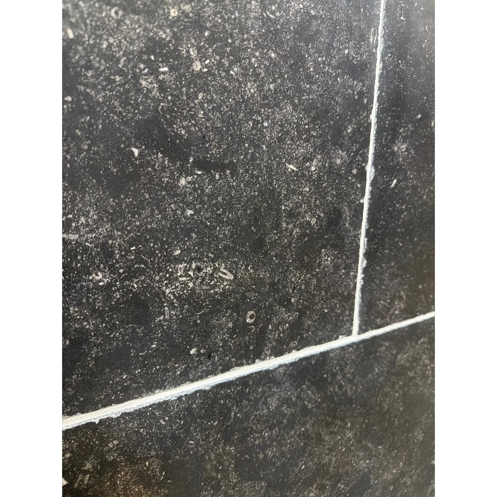 Pietra Notte Marble 16x24 tile with black surface, white grout, speckled texture
