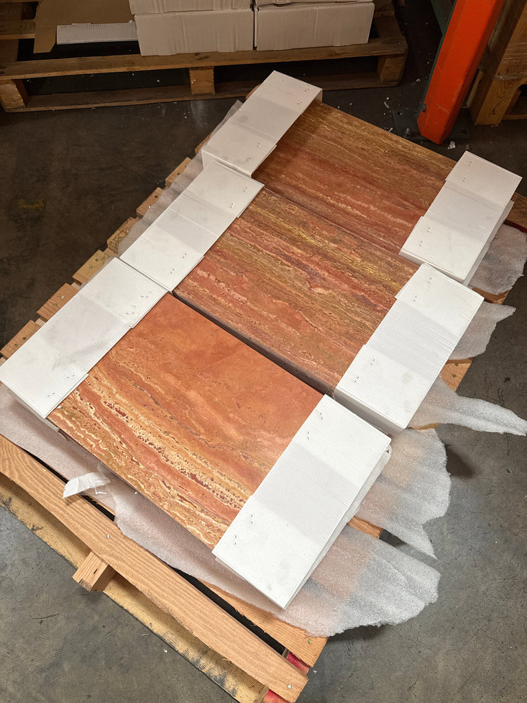Stacked orange and red travertine tiles with natural bands, secured with white strapping