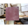 Maroon sandpaper with textured gritty surface and white dust, part of Rosso Laguna Marble product