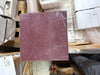 Maroon sandpaper with textured gritty surface and white dust, part of Rosso Laguna Marble product