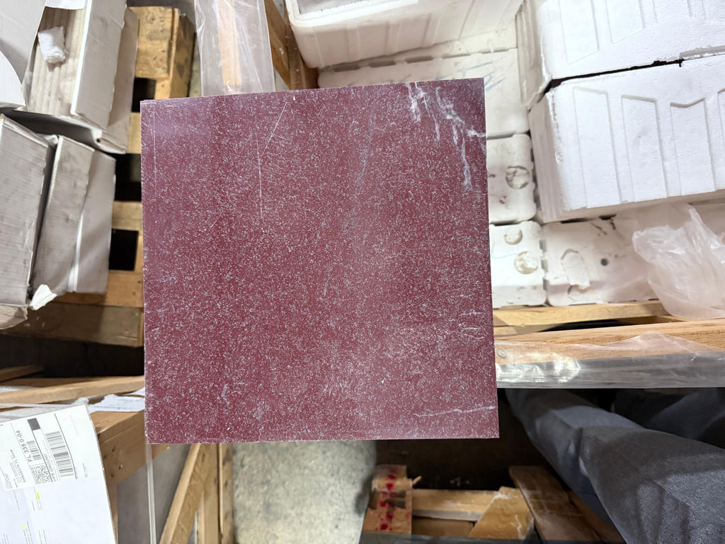 Maroon sandpaper with textured gritty surface and white dust, part of Rosso Laguna Marble product