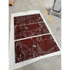 Three rectangular red rosso levanto breccia vino marble slabs with white veining on protective paper in a factory setting