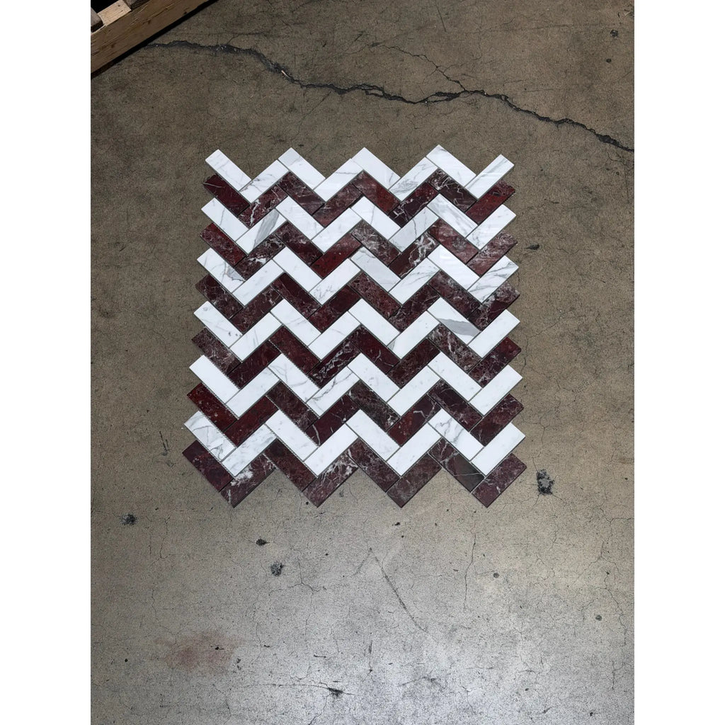 A chevron-patterned herringbone mosaic marble tile panel featuring alternating rosso levanto and italian statuary colors