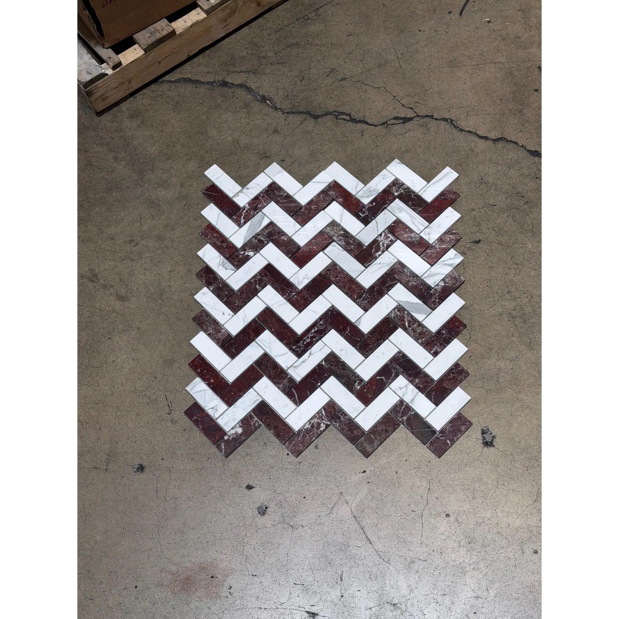 A herringbone mosaic marble tile panel featuring polished honed Rosso Levanto and Italian Statuary tiles