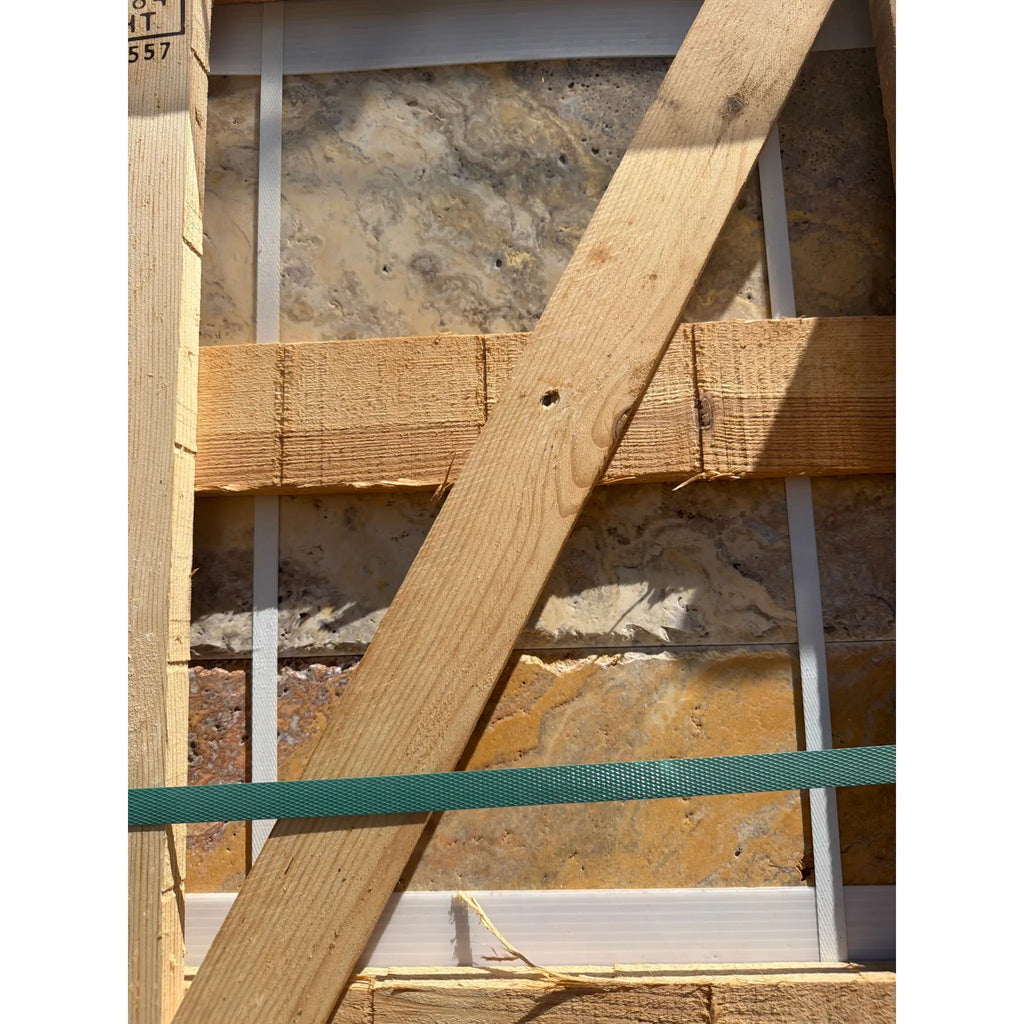 Light brown wooden beam with visible grain and small hole resting diagonally in scabos autumn leaves travertine versailles set
