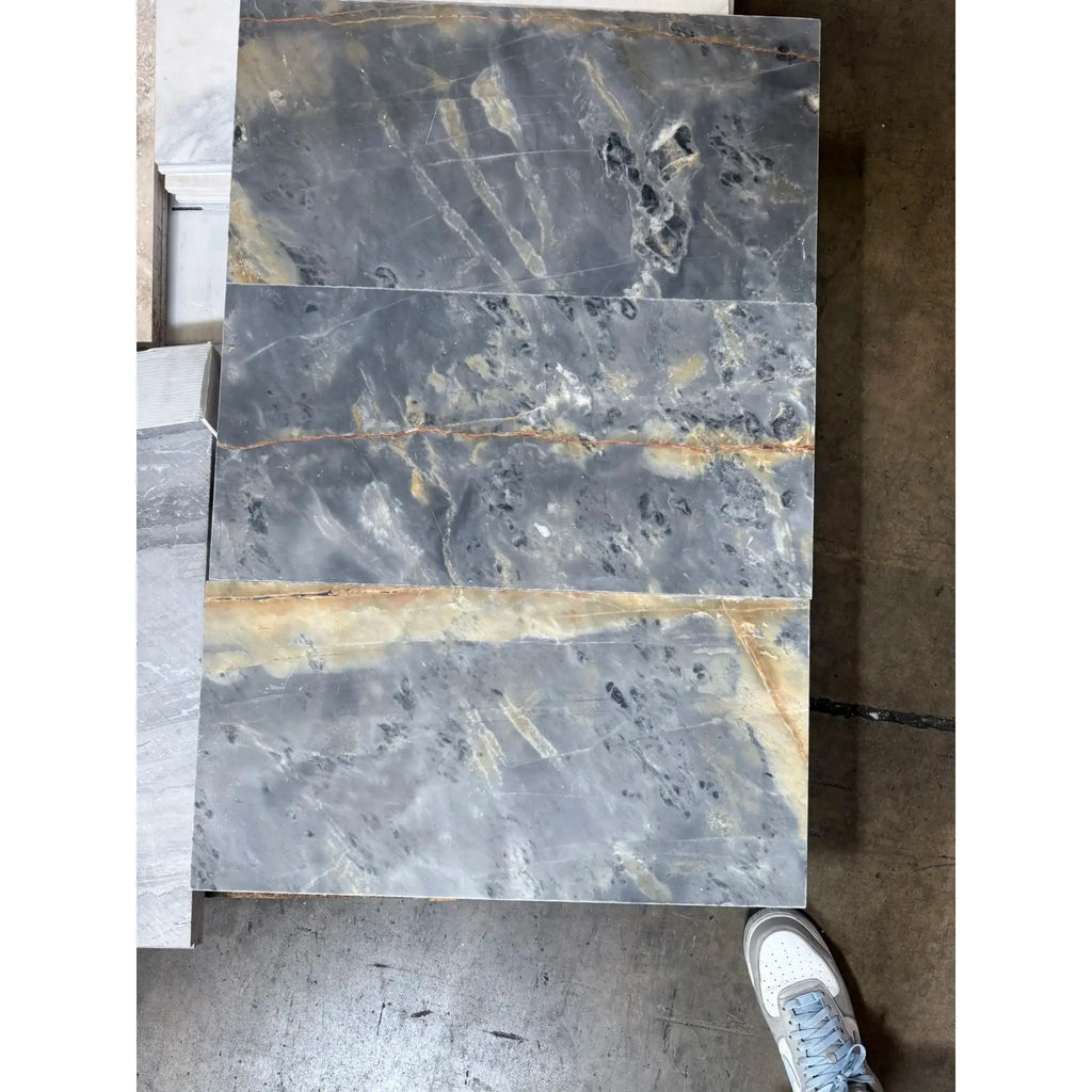 Gray marble slabs with gold veining featured in Sky Blue Azul Cielo 12X24 marble tile