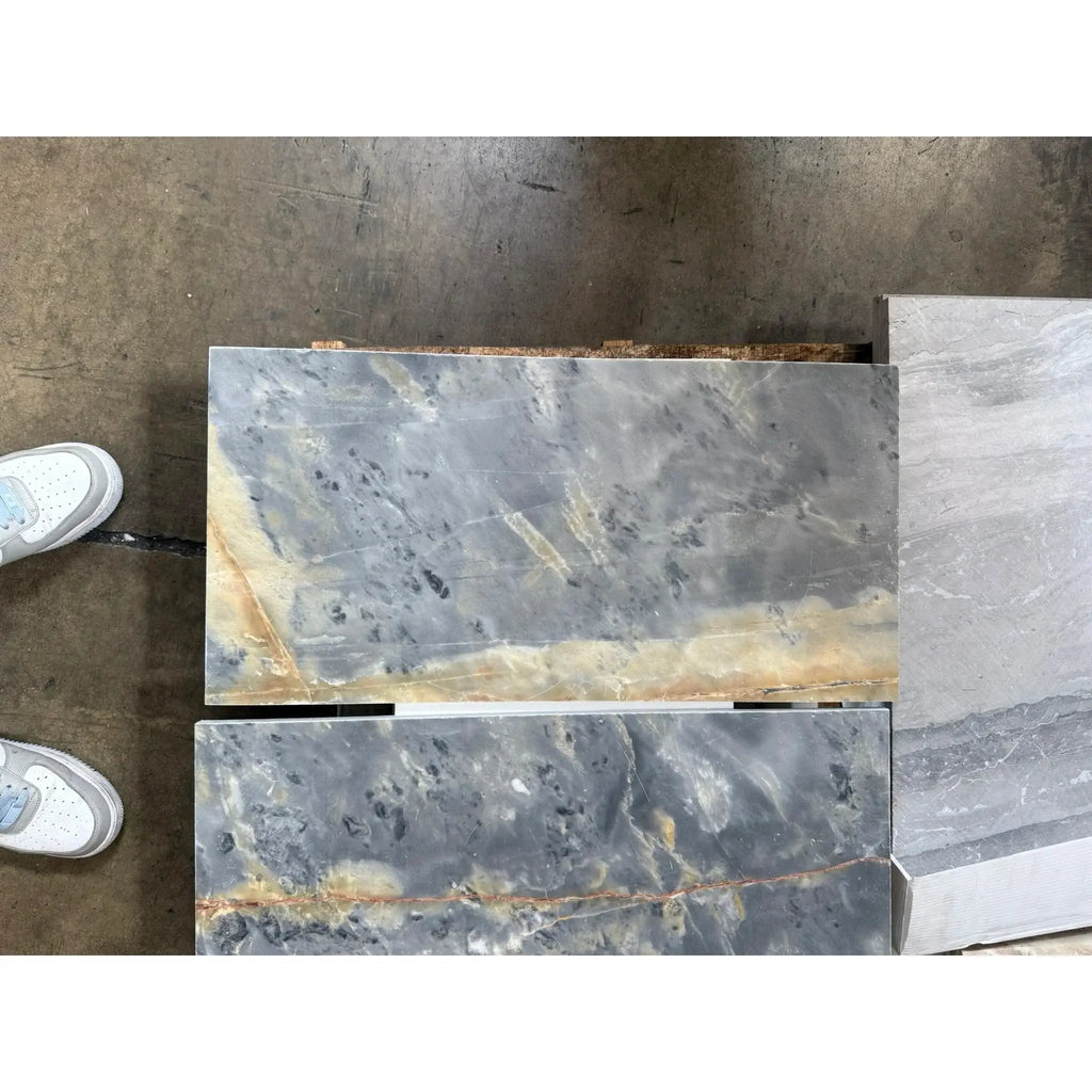 Marble slabs featuring gray and gold veining in Sky Blue Azul Cielo 12X24 Marble Tile