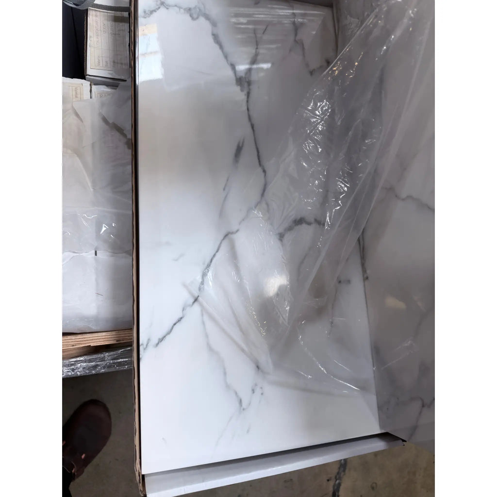 White marble-effect countertop panel with gray veining partially wrapped in clear plastic from statuario white 12x24 premium italian marble