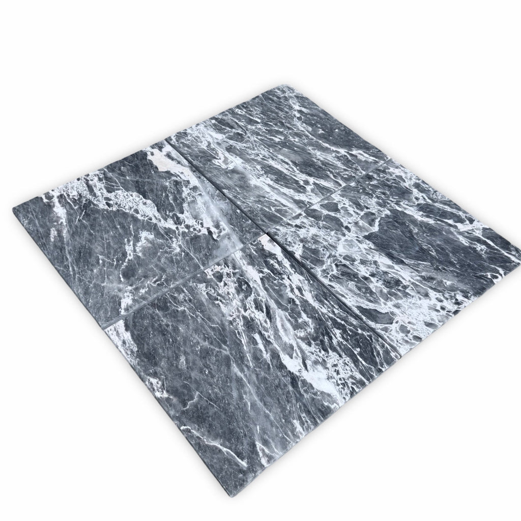 Four polished Storm Gray Marble 12x12 tiles in dark gray and white tones