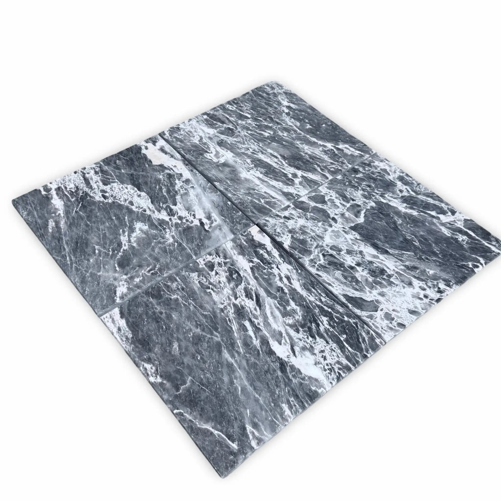 Four polished Storm Gray Marble 12x12 tiles in dark gray and white tones