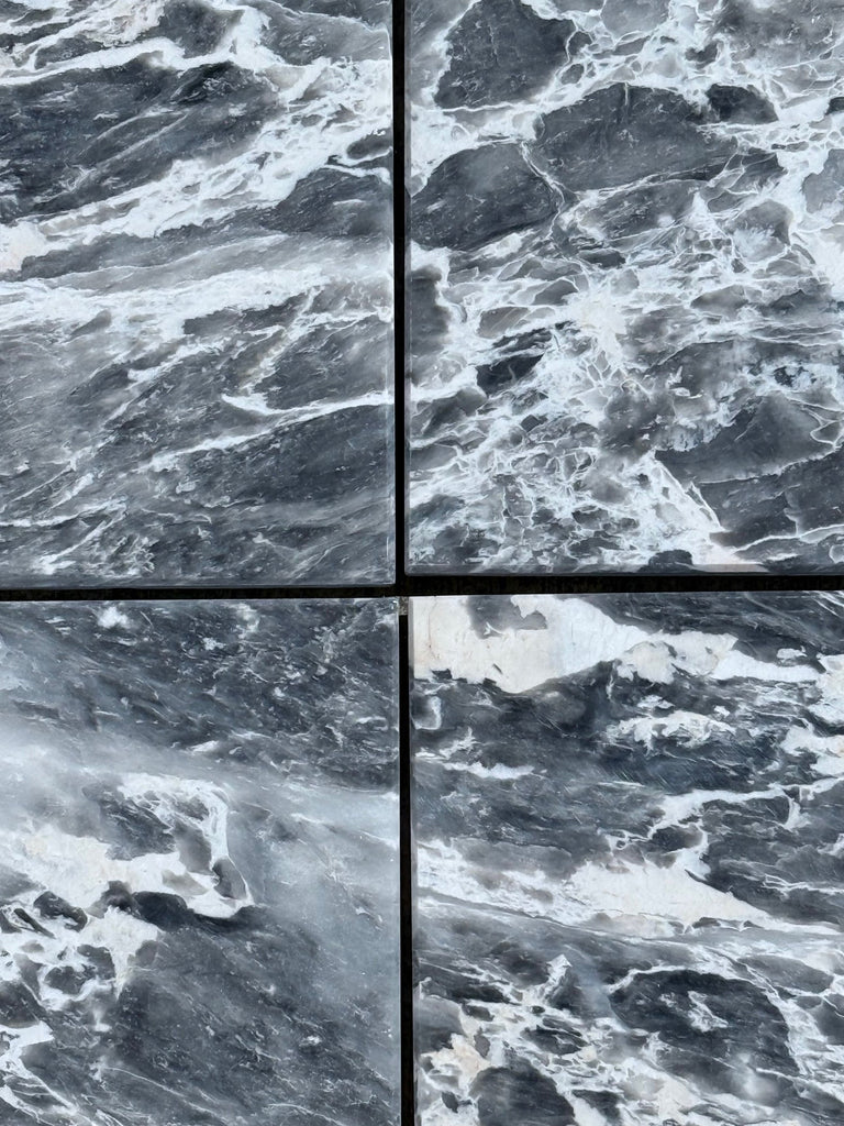 Four dark gray marble tiles with striking white veining for Storm Gray Marble 12X12 Polished