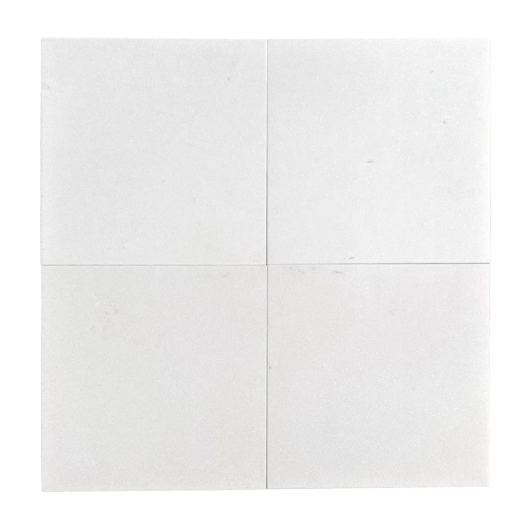 Four white square Thassos Greek marble tiles showcasing a honed finish