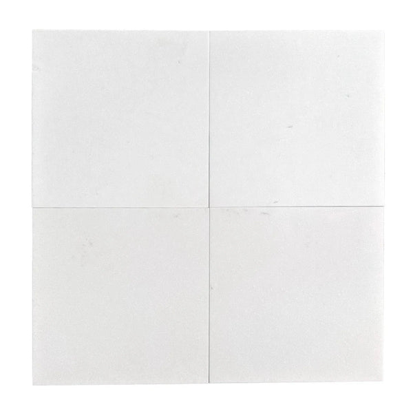 Four white square Thassos Greek marble tiles showcasing a honed finish