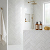 White marble thassos white 1x2 herringbone mosaic polished tiles with subtle gray veining on shower walls and countertop