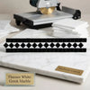 A sleek black and white diamond-patterned bias border mosaic tile on polished thassos white Greek marble slab
