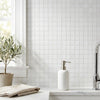 White ceramic soap dispenser with sleek brushed metal pump on thassos white 2x2 mosaic marble polished surface