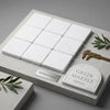 White greek marble 6x6 tumbled tiles arranged in a grid with engraved arch design and decorative text panel