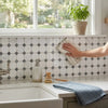 Beige striped kitchen towel with woven texture wiping a polished thassos white octagon blue-gray mosaic marble backsplash