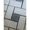 A thassos white pinwheel mosaic marble tile with a single dark gray square tile among beige rectangular tiles