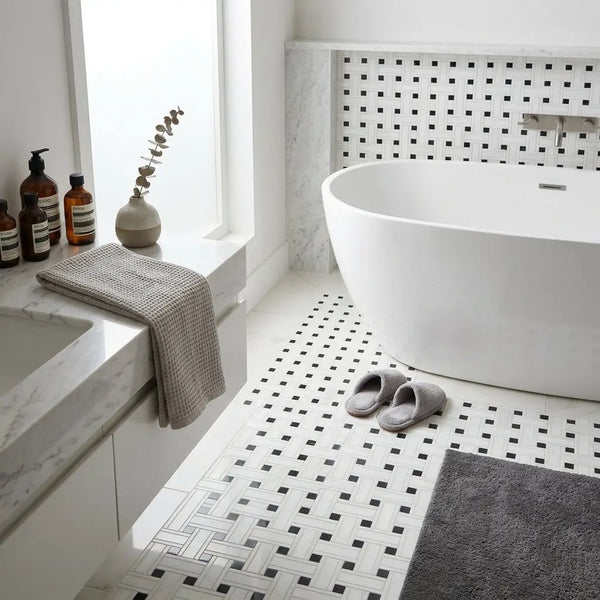 White freestanding bathtub with sleek curved edges shown with thassos white triple-weave black mosaic marble tiles