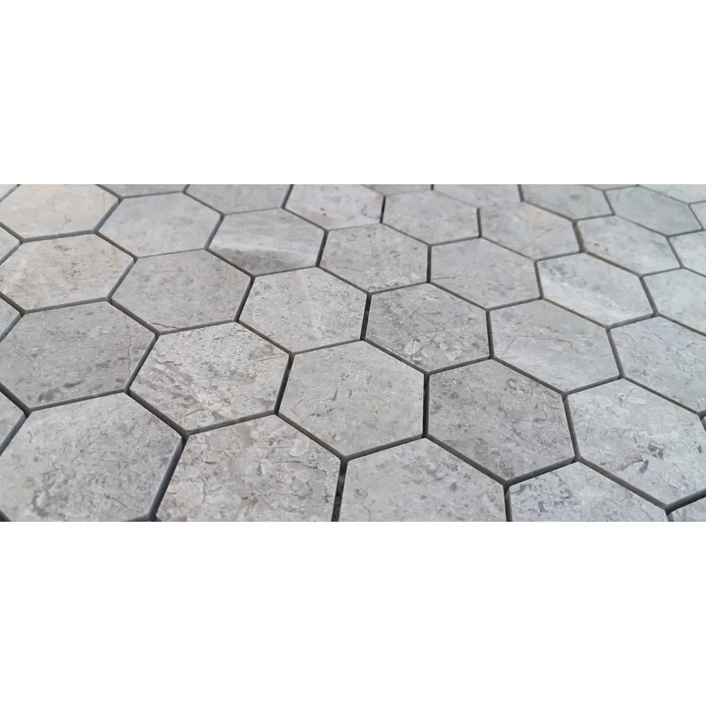 Tundra gray 2 inch hexagon marble mosaic tiles with subtle stone texture and dark grout lines polished or honed finish