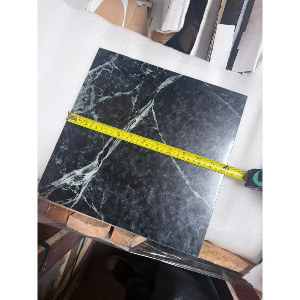 Verde Alpi empress green marble 12x12 polished tile in black with white veining measured by yellow tape measure