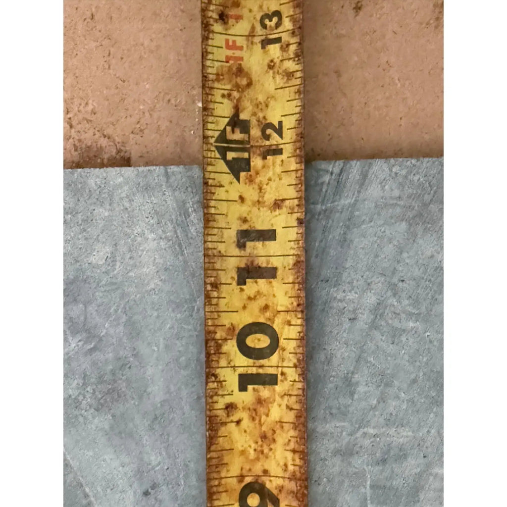 Rusty yellow measuring tape next to Verde Alpi Green Marble Tumbled product