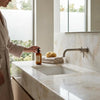 Amber glass bottle with black pump dispenser and minimalist label paired with white onyx cross cut marble tile