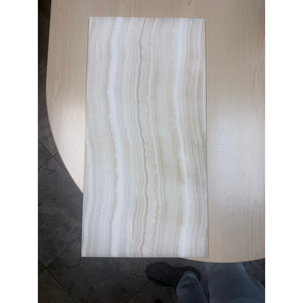 Rectangular light-colored tile with vertical wavy patterns from White Onyx Vein-Cut Marble