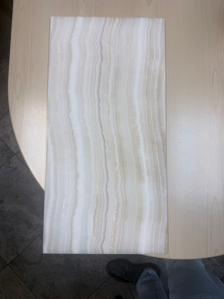 Rectangular light-colored tile with vertical wavy patterns from White Onyx Vein-Cut Marble