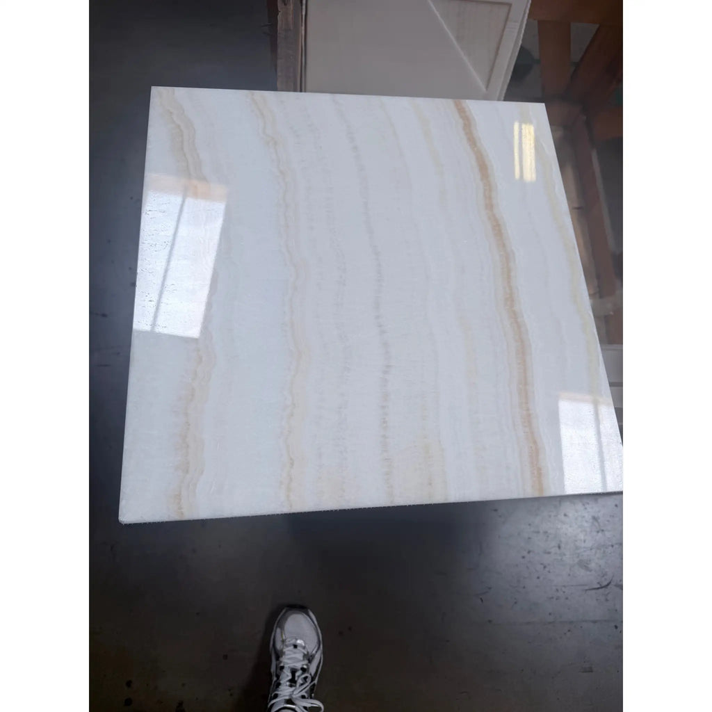 A polished 18x18 white onyx marble tile with glossy white surface and subtle beige veining called vanilla onyx vein-cut