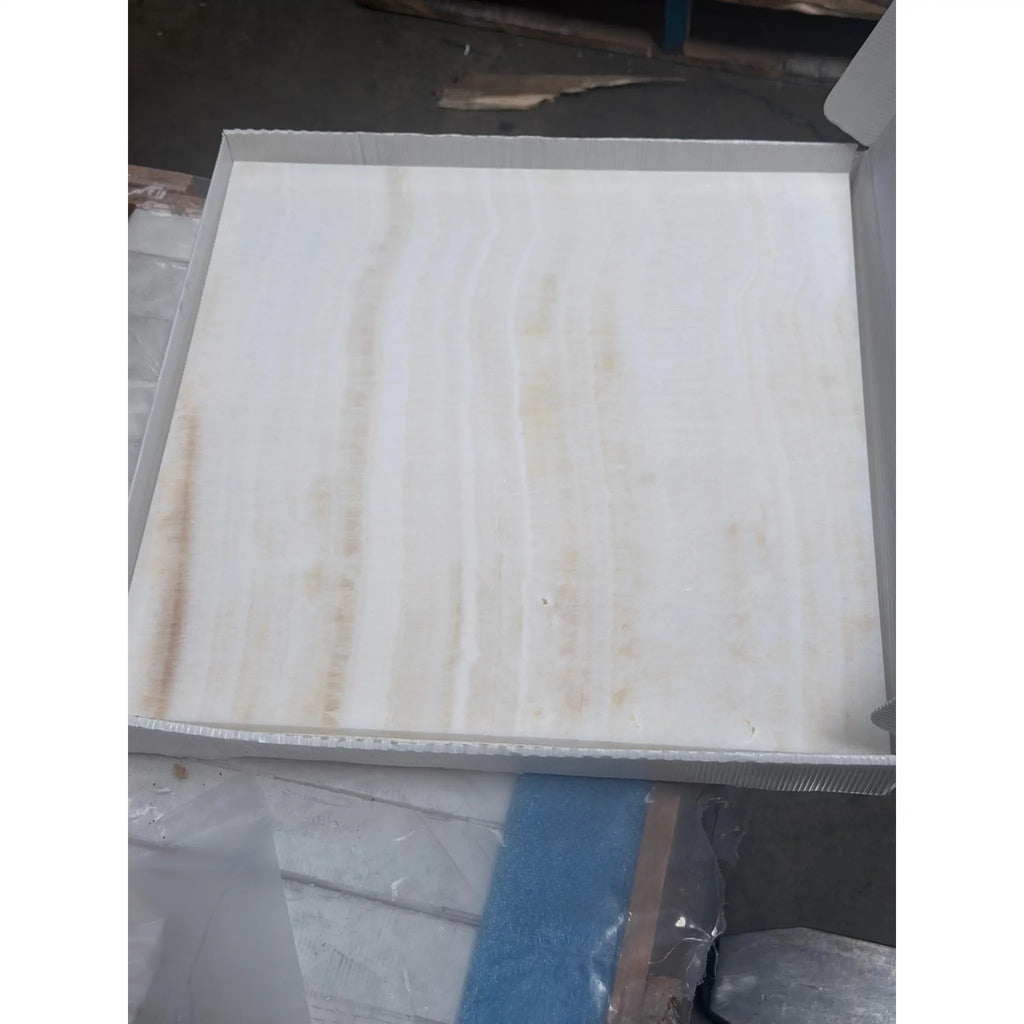 A polished square white onyx marble tile with subtle beige veining in an 18x18 vein-cut finish