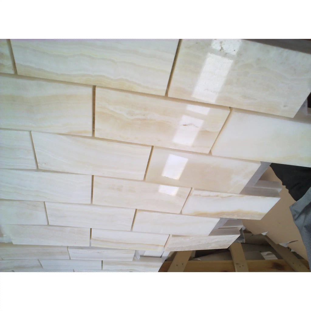Beige marble subway tiles with subtle veining and a glossy finish in white onyx vein-cut 2x4 mosaic polished design