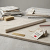 A sleek light beige turkish marble rolling pin with gray veining on a polished white pearl botticino marble slab liner molding