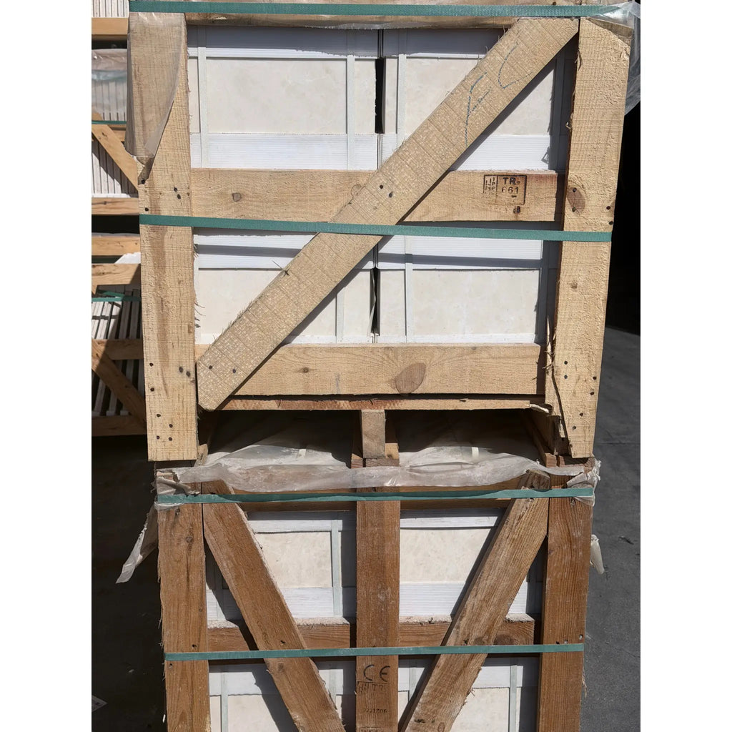 Stack of white pearl botticino beige marble 12x12 polished or honed tiles secured in a wooden crate with green straps