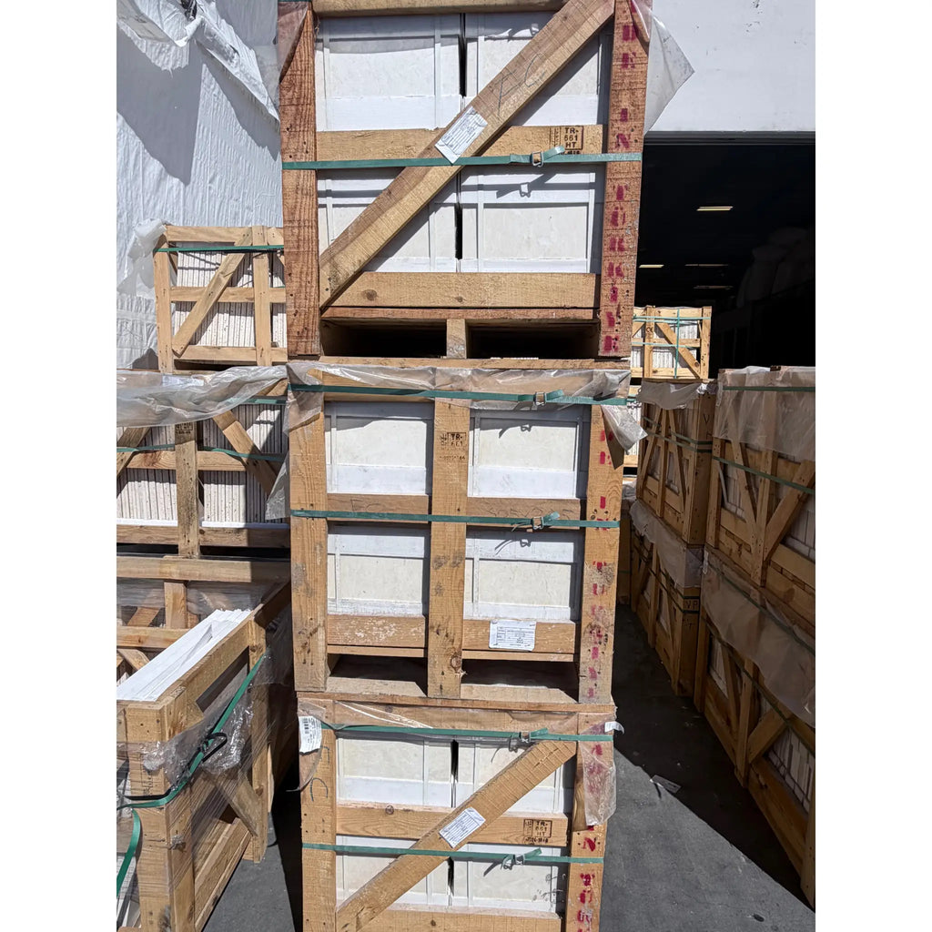 Stacked wooden crates holding white pearl botticino beige marble 12x12 polished or honed panels secured with green straps