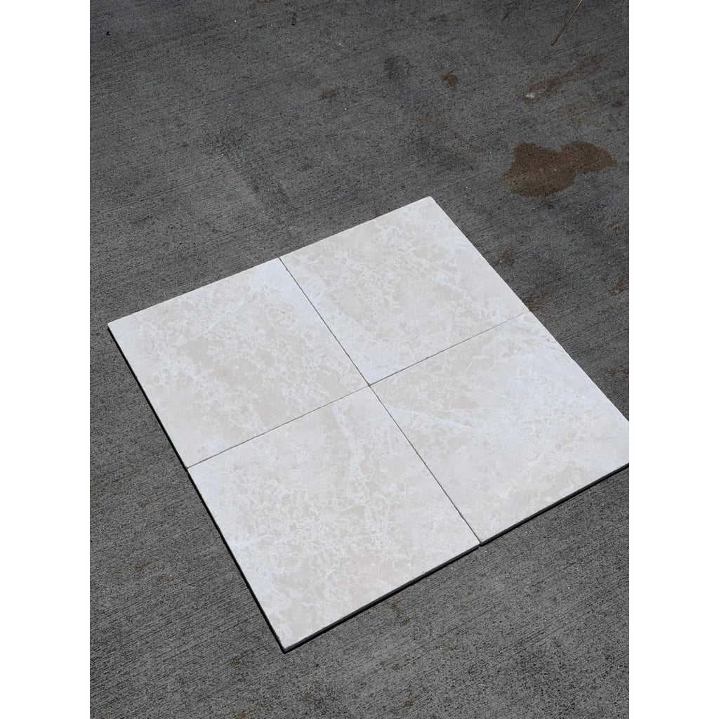 Four square light beige white pearl botticino marble 12x12 tumbled tiles with subtle veining arranged in a grid