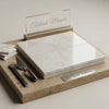 A sleek polished white pearl Turkish marble tile with subtle veining rests on a wooden display board